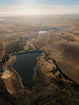 An aerial approach to a dam among lands at sunrise