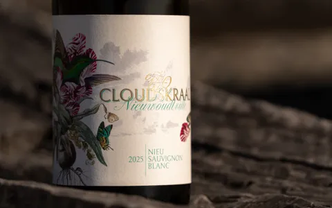 The 2025 Nieu Sauvignon Blanc label caught by a band of light on a rock