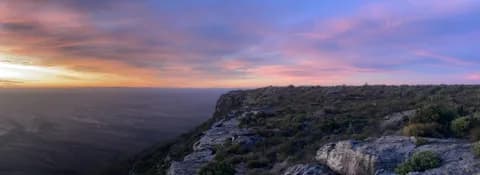A broad panorama of the krans under a changing pink and blue sky