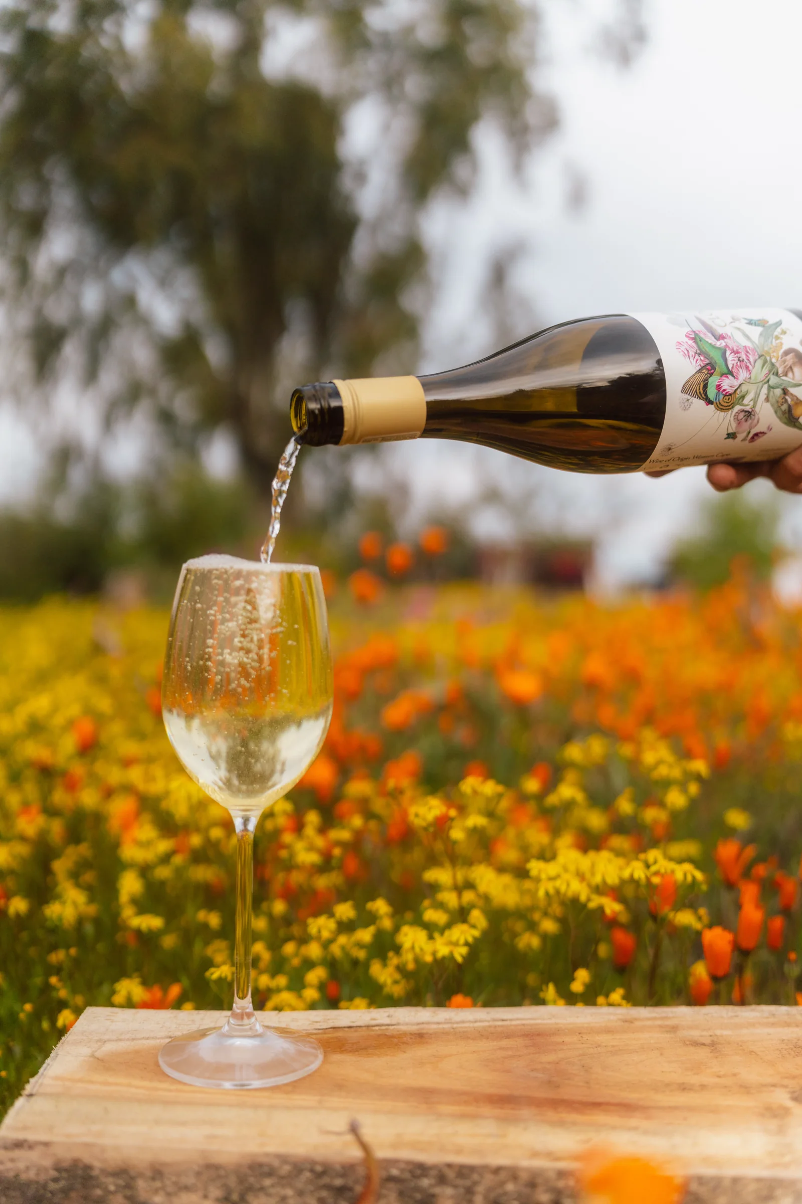 Wine poured into a glass on a wooden board, spring flowers behind